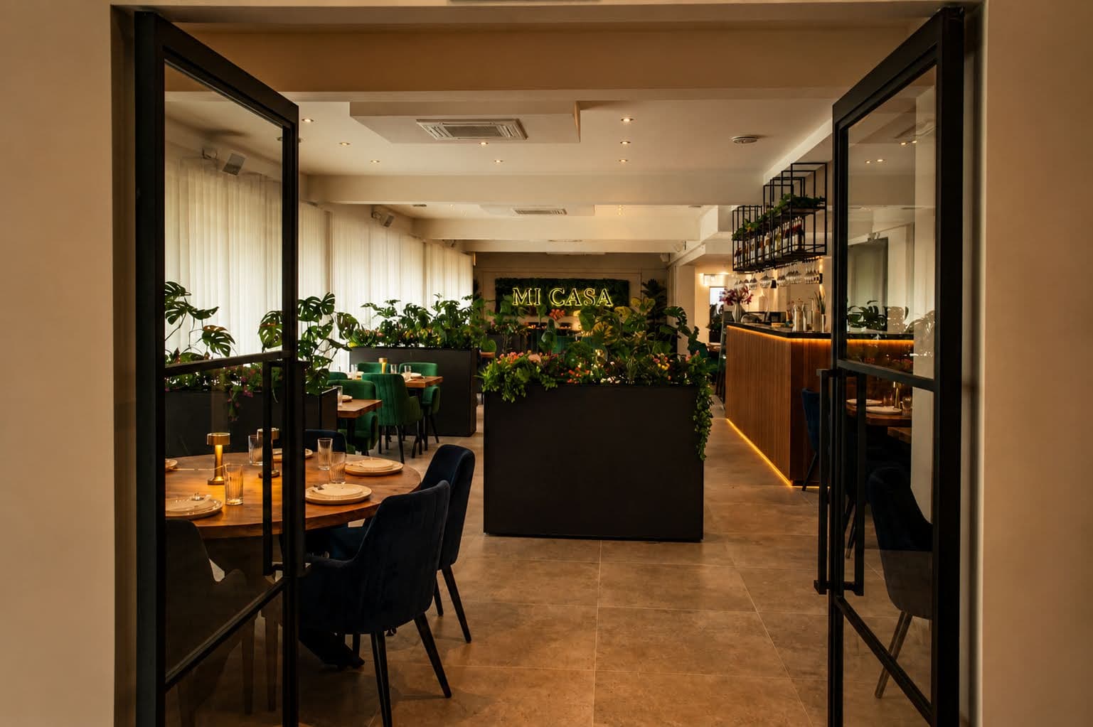 Mi Casa zaak met groene stoelen, plantenwand en neonlogo
